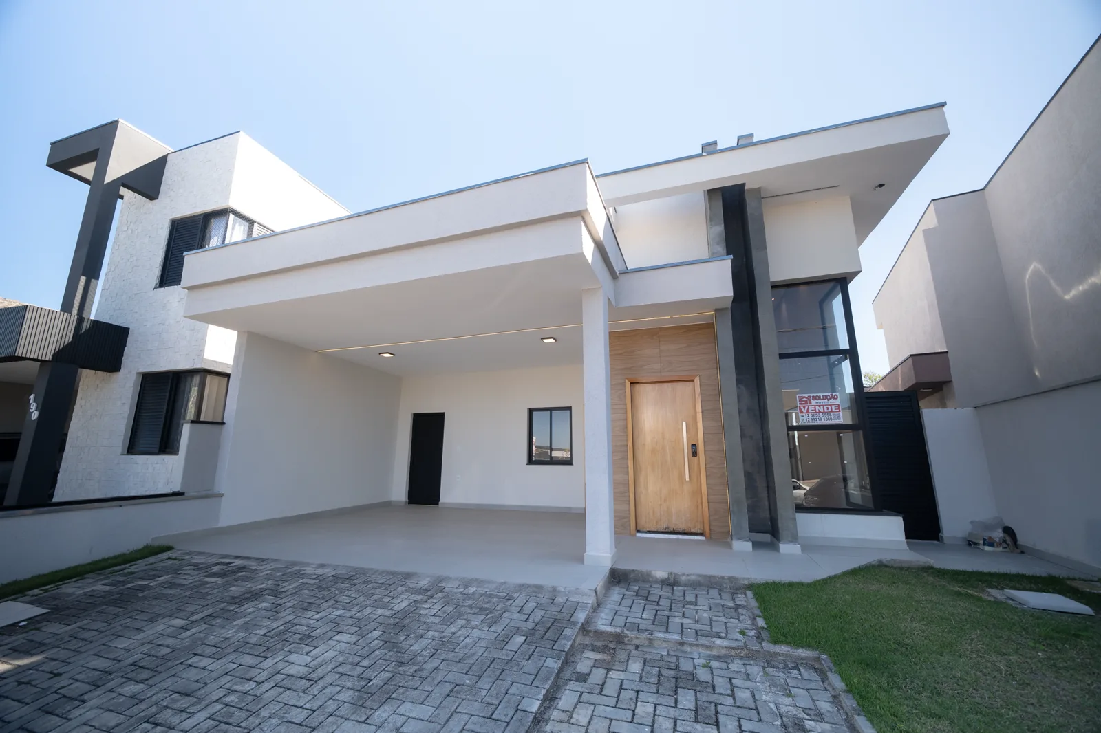 A fachada da casa, com garagem coberta e jardim frontal.